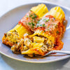 A fork taking a bite of pasta stuffed with
turkey, spinach, ricotta, topped with red
sauce and garnished with parsley