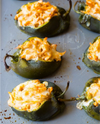 6 halved poblano peppers stuffed with shredded buffalo chicken and topped with melted cheese on a sheet pan