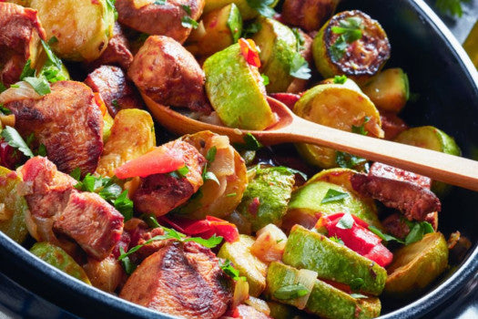 Serving bowl of cubed chicken, eggplant, red pepper, zucchini, onion, and mushrooms in a diced tomato sauce