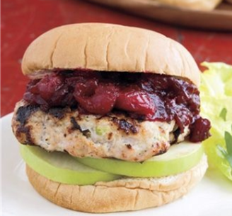 A bun with a chicken patty, green apples, and cranberry sauce in between