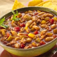 A yellow chili bowl with beans, turkey meat, squash, and tomatoes 