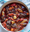 Soup pot filled with simmered beef cubes, potatoes, carrots, red bell pepper, onion, and celery

