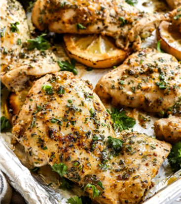 Sheet pan of garlic butter chicken breasts topped with lemon slices, herbed olive dressing, and crumbled goat cheese

