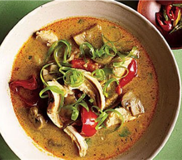 Bowl of Thai coconut soup full of chicken, red bell pepper, sliced mushroom, garnished with cilantro and green onion

