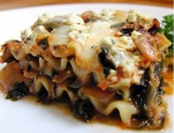 Plated square serving of 3 layer spinach artichoke lasagna topped with melted cheese

