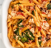 Penne pasta tossed with wilted spinach, halved cherry tomatoes, wilted spinach, crumbled feta cheese in a creamy sauce