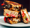 A white plate with stacked and halved grilled cheeses stuffed with roasted pepper and brocolli