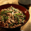  A brown bowl with barley risotto mixed with mushrooms and greens