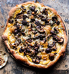 Homemade pizza with cheese, delicata squash, and mushrooms
