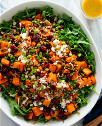 Roasted sweet potatoes with pepitas, feta, cranberry raisins, and a homemade ginger dressing over a bed of arugula